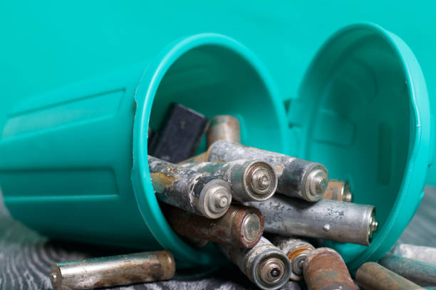istock Trash can with a lid, capsized on its side. Tank filled with waste batteries. The batteries are covered with corrosion. Symbol of environmental protection day. 1221437362