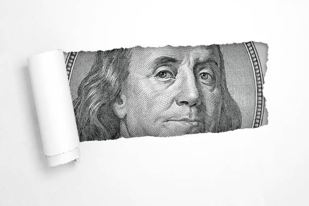 istock Benjamin Franklin on a Hundred Dollar Bill in the Hole of Torn White Paper. 3d Rendering 1221440002
