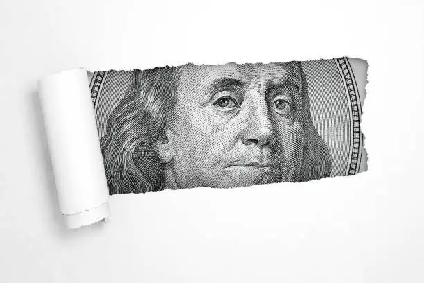 Photo of Benjamin Franklin on a Hundred Dollar Bill in the Hole of Torn White Paper. 3d Rendering