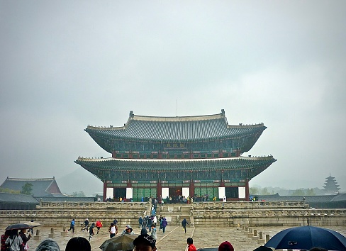 Seoul, South Korea: Tourists with and without umbrellas in front of Gyeongbokgung palace in the center of Seoul, built in 14th century.