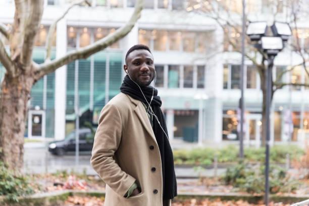 istock Young Black Man in Beige Coat with Head Turned Towards Camera 1221444102