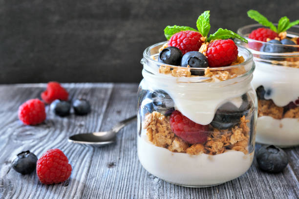 istock Healthy blueberry and raspberry parfaits in mason jars on dark background 1221444400