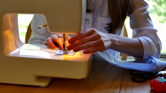 Unrecognizable woman uses sewing machine