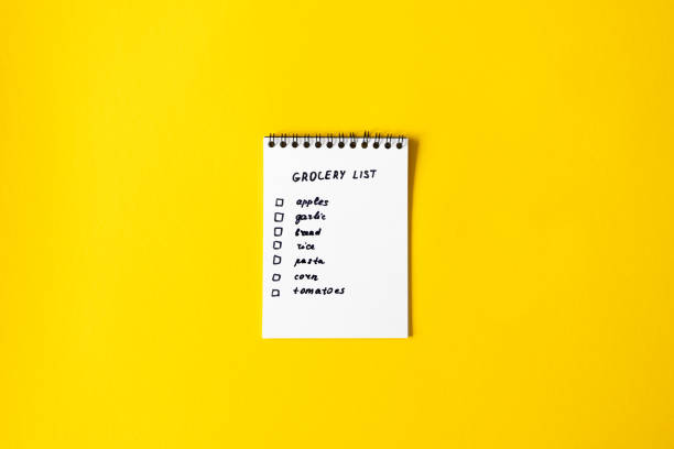 bloc-notes en papier de liste d’épicerie sur le fond jaune avec l’espace de copie, vue supérieure - liste de courses photos et images de collection
