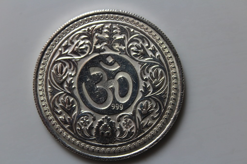 Ohm symbol on a silver coin with white background.