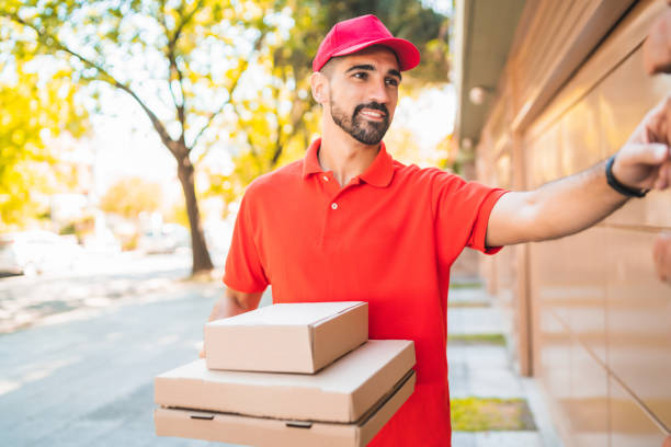 istock Delivery man with pizza box ringing house doorbell.. 1221451111