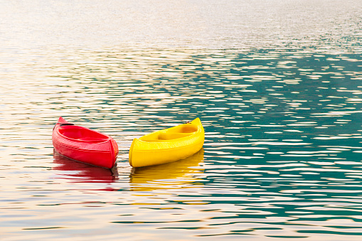 Kayaking. Bright red and yellow kayaks on open sea waves in sunset light. Right Side Copy Space. Water Sports and Summer Recreations outdoor activities Theme.