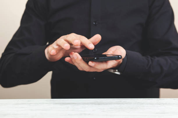 istock Man is holding new mobile phone in hands, scrolling, tapping and typing, touching screen 1221453606