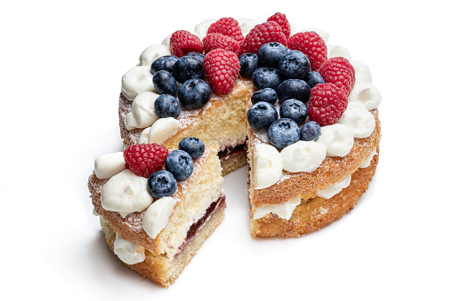 Victoria sponge cake with whipped cream and berries on top isolated on white