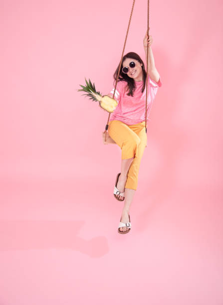 istock Young woman on a swing on a pink background. 1221458058