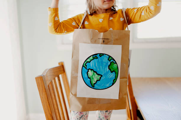 Mała dziewczynka na sobie papierowa torba Na dzień ziemi kostium – zdjęcie