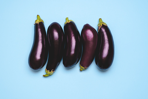 Aubergines on a blue table top view. Organic eggplants top view. Fresh purple vegetables on a blue backgroungd