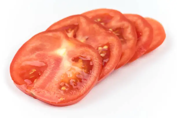 Macro closeup sliced tomato over white background copy space.