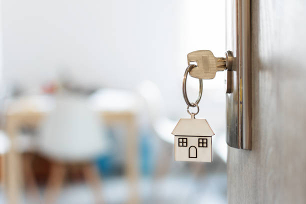 Key with keychain in a house shape in the door keyhole. Buy new home concept. Opened door to a new house. Key with keychain in a house shape in the door keyhole. Buy new home concept. Real estate market. house key stock pictures, royalty-free photos & images
