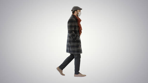 istock Gentleman wearing a protective face mask walking on gradient background 1221462371