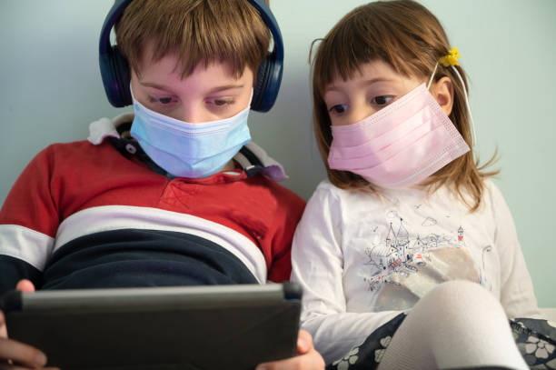 istock Brother and sister with masks at home 1221462379