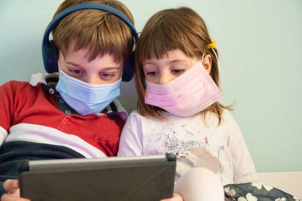 istock Brother and sister with masks at home 1221462531