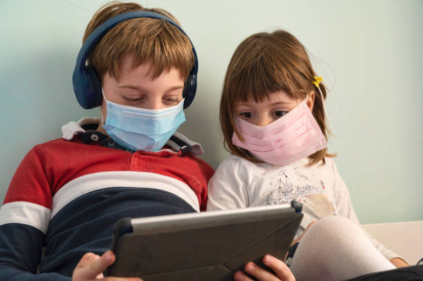 istock Brother and sister with masks at home 1221462583