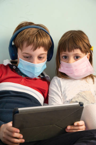 istock Brother and sister with masks at home 1221462620