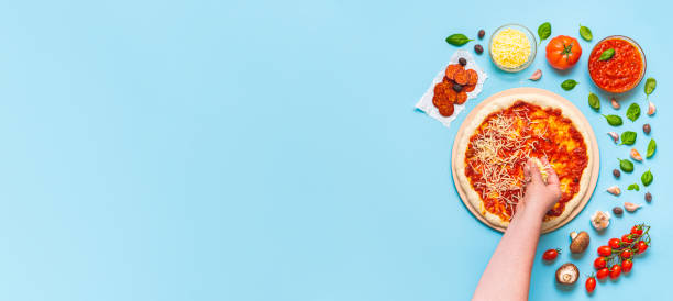 Putting cheese toppings on pizza, above view