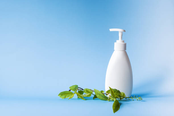 istock White bottle with a dispenser for liquid soap next to cherry leaves on a blue background. Body care, beauty copyspace 1221463986