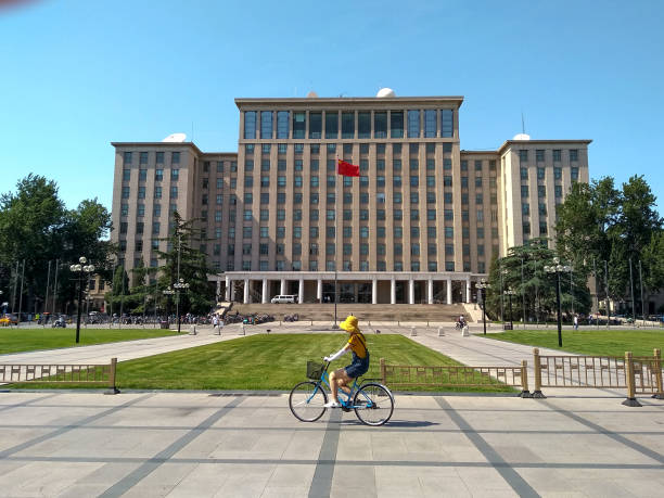 estudiantes en bicicleta frente a la entrada principal de la universidad de tsinghua en beijing, china - tsinghua fotografías e imágenes de stock