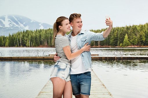 Front view of aged 18-19 years old caucasian teenage boys photography wearing button down shirt who is embracing who is photographing and using mobile phone