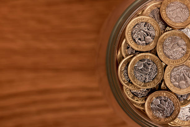 背景に瓶の中の英国のお金 - piggy bank gold british currency pound symbol ストックフォトと画像