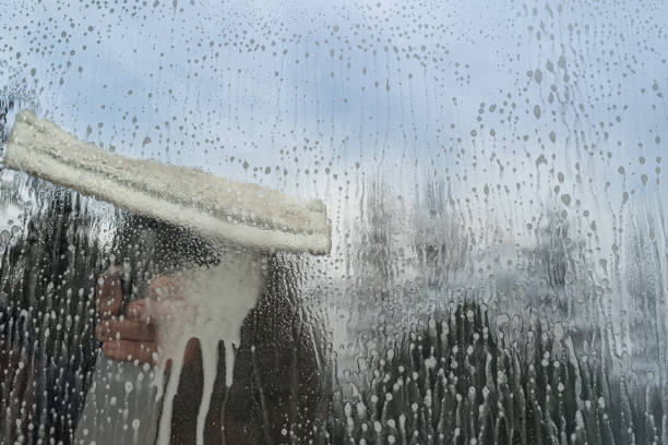istock Caucasian man washing glass with microfiber window washer. 1221467366