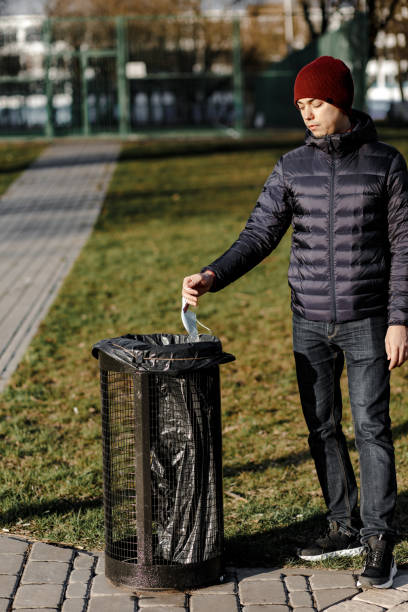 istock guy throw a disposable mask in the trash. 1221467639