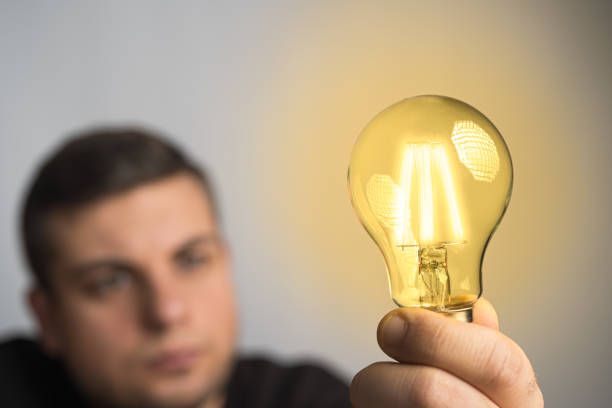 istock Caucasian man holding glowing incandescent light bulb. 1221467665