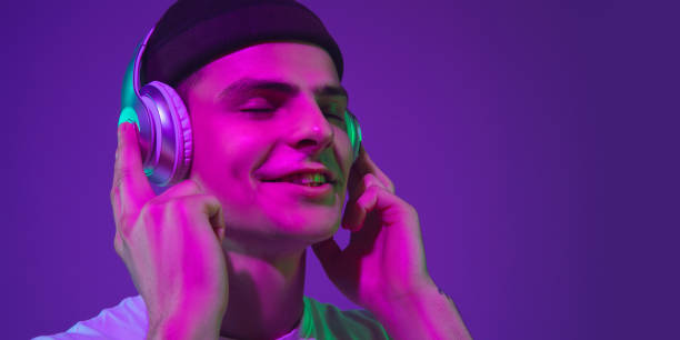 istock Caucasian man's portrait isolated on purple studio background in neon light, flyer 1221468302