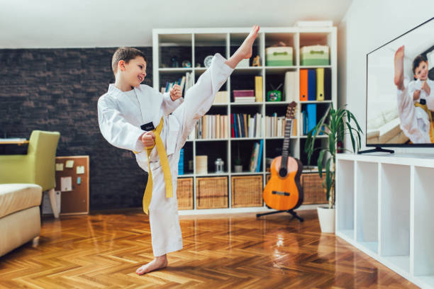 garçon de taekwondo exerçant à la maison dans le salon. - living room learning healthy lifestyle one person photos et images de collection