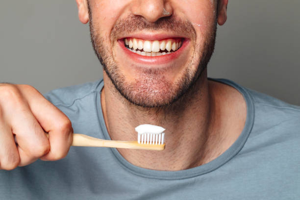 Dental Hygiene: Cropped Image of a Smiling Man about to Brush His Teeth Oral hygiene: mouth of a man ready to brush his teeth. tooth in hand stock pictures, royalty-free photos & images