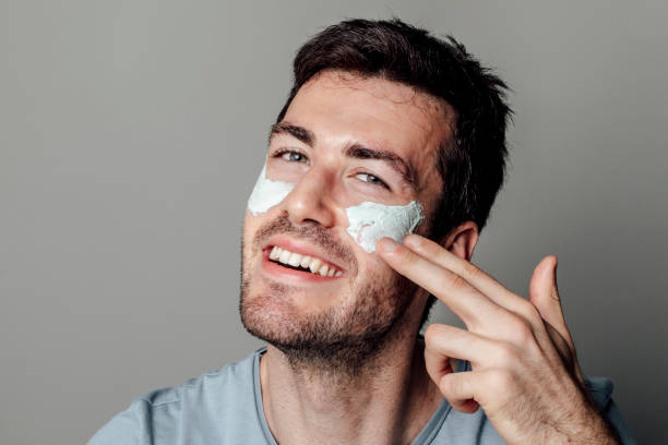 istock Men's Beauty Rituals: Happy Handsome Man Applying Moisturizing Facial Mask 1221471776