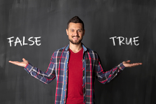 Young man in front of blackboard with text 
,, False, True 