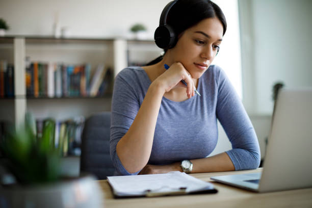 ヘッドフォンは、自宅で仕事を持つ若い女性 - office worker audio ストックフォトと画像