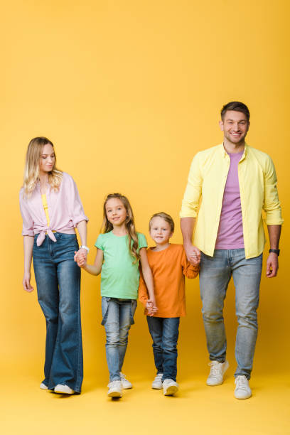 istock happy parents holding hands with kids on yellow 1221478633