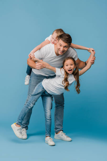 istock smiling father piggybacking and plating with kids on blue 1221478661