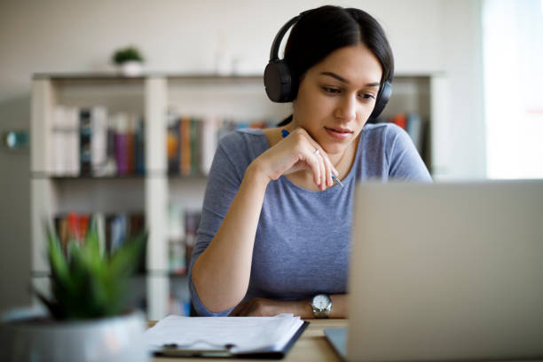 istock Young woman with headphones working from home 1221479433