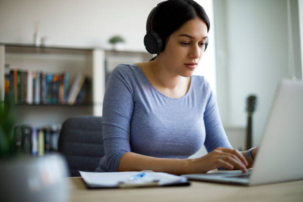 istock Young woman with headphones working from home 1221479434