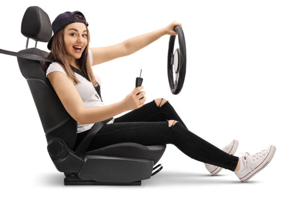 Young female in a drivers car seat holding a key isolated on white background