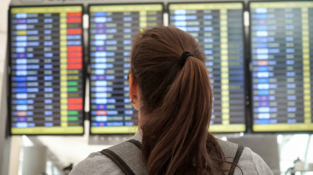 morena mira el horario de salidas en la terminal del aeropuerto - ponytail brown hair tourist women fotografías e imágenes de stock