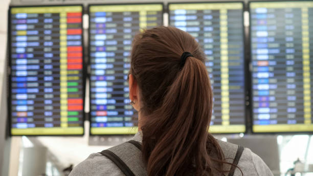 bruna guarda il programma partenze nel terminal dell'aeroporto - ponytail brown hair tourist women foto e immagini stock
