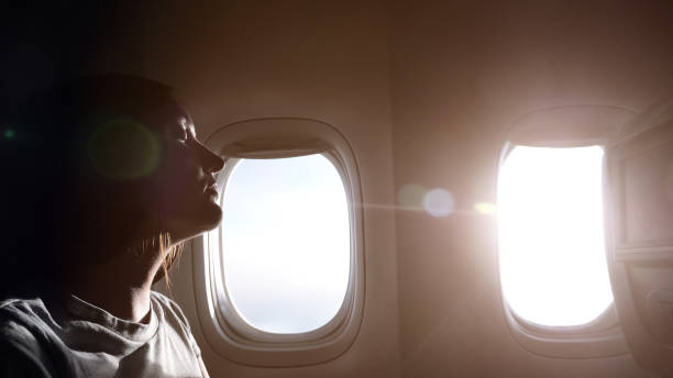 istock woman half-face silhouette against airliner windows closeup 1221479595