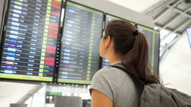 bruna guarda il programma partenze nel terminal dell'aeroporto - ponytail brown hair tourist women foto e immagini stock