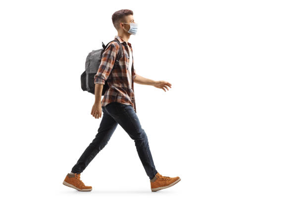 istock Young guy with a backpack wearing a protective medical mask and walking 1221480149
