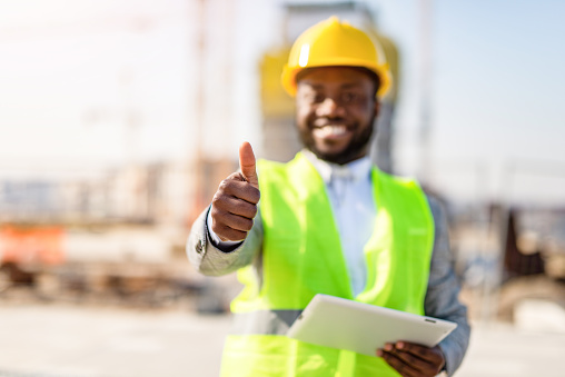 Young architect using a digital tablet on a construction site. Showing thumb up.
