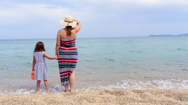 istock Mother And Little Daughter Walking Along Tropical Beach 1221481121