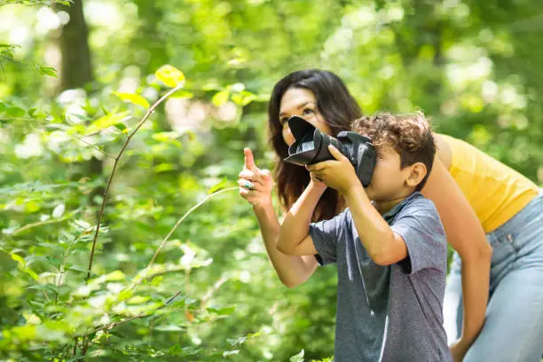Photo of Little boy taking photo with her mother in the woods.